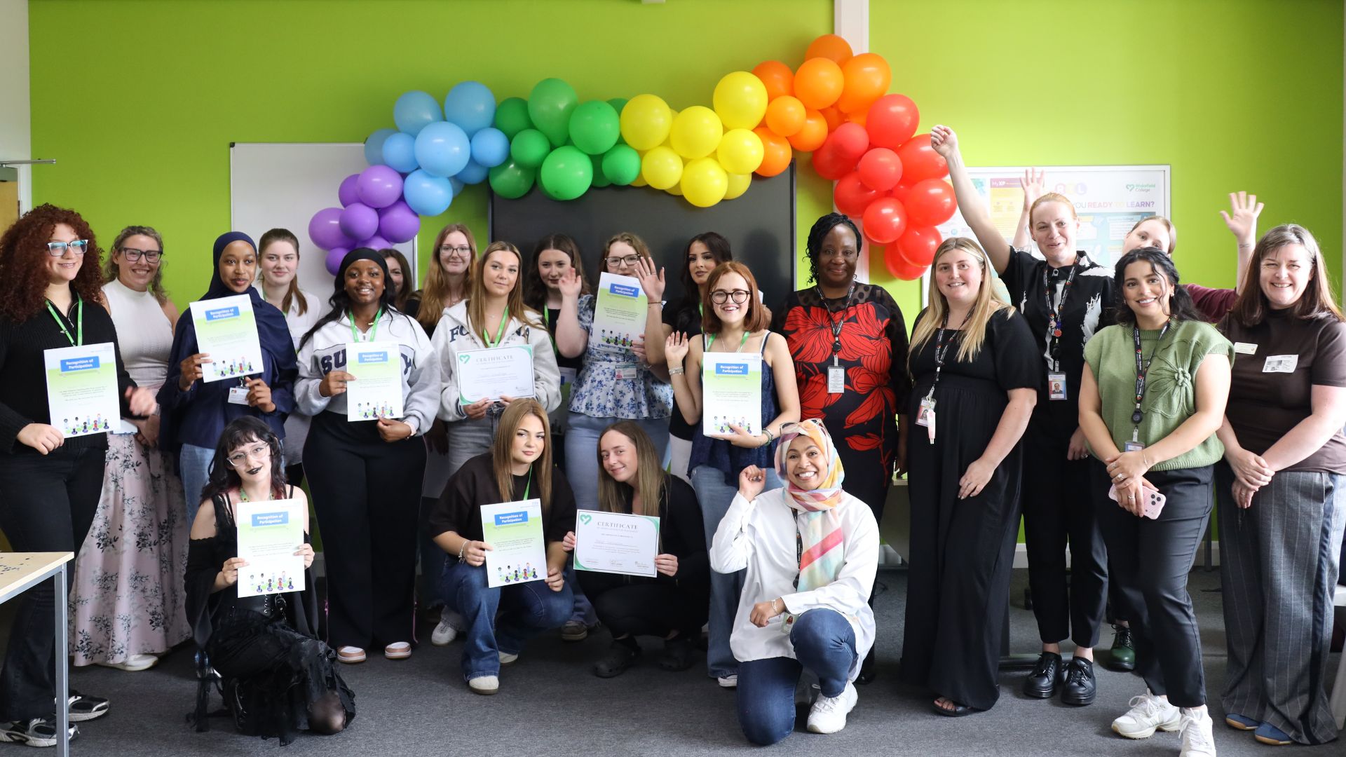 Photo of students and tutors with certificates and balloons.